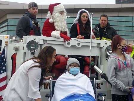Santa with child patient on fire truck ladder